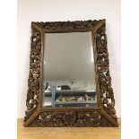 A modern wall mirror with rectangular bevelled glass, within a carved and pierced frame (87cm x