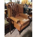 A Georgian inspired wing back armchair in mocha upholstery, with button back, scroll arms and