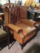 A Georgian inspired wing back armchair in mocha upholstery, with button back, scroll arms and