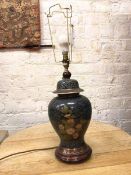 A ceramic Chinese style lamp in the form of a lidded baluster vase, with floral decoration, on