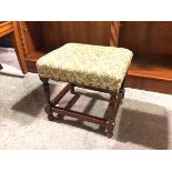A 1930s/40s footstool with foliate upholstered top on turned supports united by stretchers (34cm x