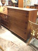 A mid century teak chest of drawers, the rectangular top above five graduated drawers, on straight