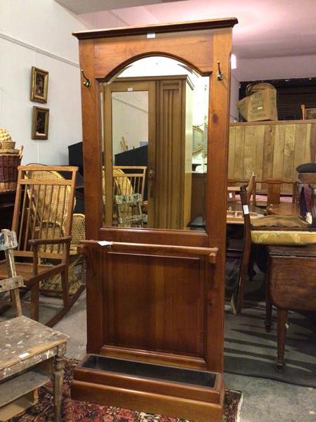 A modern hallstand with moulded cornice above a domed bevelled mirror, with two hanging hooks, above