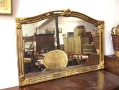 A modern wall mirror within an elaborate frame, with domed top and fleur de lys crest, with mirrored