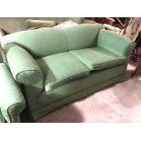 A two seater sofa with concave back above scroll arms, in green upholstery with multiple stylised