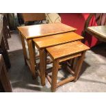 A set of three teak nesting tables, each with moulded apron (largest: 47cm x 52cm x 34cm)