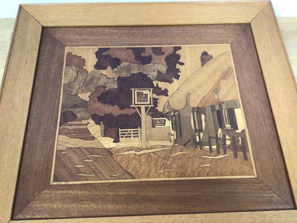 A marquetry panel depicting a thatched roofed pub, the sign possibly with a Cat and Fiddle (with