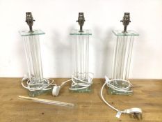 A set of three glass table lamps with a square top on multiple glass rod stem, on tiered glass base,