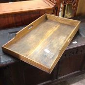 An Edwardian oak tray, with raised edges and pierced handles to sides (49cm x 72cm x 44cm)