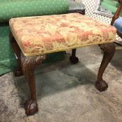 A 1920s Georgian style footstool with later upholstered top, carved knees and ball and claw feet (