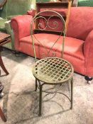 A metal garden chair, the arched back with a stylised pierced heart splat above a lattice seat, on