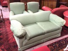 A two seater sofa with concave back above scroll arms, green upholstery with multiple stylised