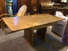An Art Deco walnut extending dining table, with two draw leaves, on moulded supports united by