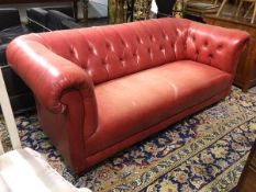 A Chesterfield sofa in red leather with button back and sides, rolled arms, on turned supports (78cm