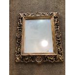 A rectangular wall mirror, the glass within a gilt composition frame with pierced foliate and