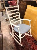 A modern wooden rocking chair, painted white, with ladder back, blue upholstered seat, on turned