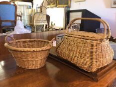 A pair of wicker baskets, one of oval form with raised handles to sides, the other of funnel form,