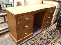 A modern pine dressing table, the rectangular top with moulded edge and shaped front, on two