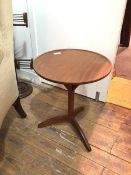A mid century teak occasional table, the dished circular top on three supports on a faceted stem
