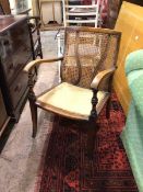 A 1930s/40s armchair, the cane back with two curved banisters above an upholstered seat, on tapering