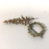 A wreath style 9ct gold brooch, with peridot set stones divided by leaves (2.5cm) and a bar