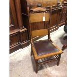 An Arts & Crafts nursing style chair with a comb and plank back, with leather upholstered seat, on