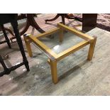 A contemporary coffee table, the square glass top on a beech frame, with straight square supports (