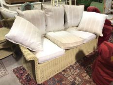 A three seater painted cane wicker sofa with three seat and back cushions and two scatter