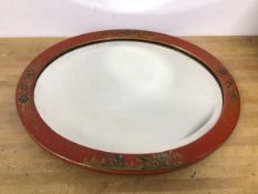 An early 20thc oval mirror, the glass within a red lacquer frame with gilt chinoiserie decoration (