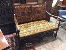 A 1920s/30s two seater sofa with cane back with central carved rosette, the arms on turned