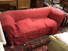 A late 19thc/early 20thc sofa, with scroll arms, with later red cover over earlier upholstery, on