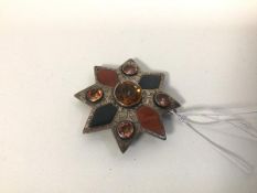 A white metal brooch set paste stones and inlaid polished stones, of star shape (6cm)