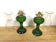 A pair of green glass oil lamps, complete with shades (lamp: 24cm excluding shade)