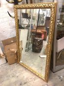 A contemporary wall mirror, the rectangular glass within a gilt frame with foliate decoration (118cm