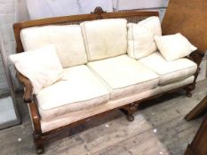 A three seater sofa, the cane back with shell surmount, with caned sides and scroll arms, with