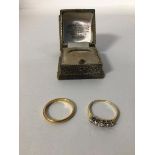 Two yellow metal rings, one a wedding band (S), the other set five paste stones