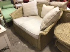 A painted wicker verandah sofa, with single seat cushion and scroll arms (86cm x 147cm x 90cm)