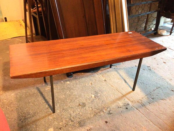 A 1970s coffee table, with rectangular top with canted edges to long sides, above a shaped apron, on