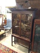 A 1920s Georgian revival bookcase on stand, with pierced swan neck pediment (a/f), above a dentil