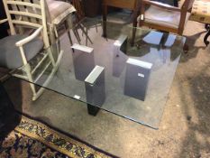 A contemporary coffee table with square glass top on four rectangular metal mirrored supports (