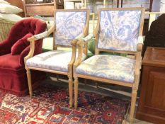 A pair of Louis XVI inspired beech open armchairs, with shaped arms and foliate upholstery, on