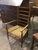 A late 19thc/early 20thc elm low chair with ladder back above a rush seat, on turned supports united