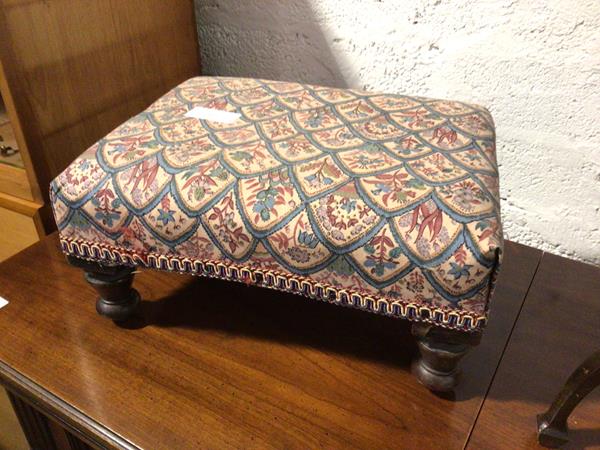 A 1920s/30s footstool with later floral upholstery on turned supports