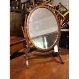 An Edwardian dressing table mirror, the oval glass on scroll supports with trestle base (57cm x 39cm