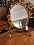An Edwardian dressing table mirror, the oval glass on scroll supports with trestle base (57cm x 39cm