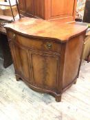 A reproduction side cabinet, the serpentine top above a frieze drawer and two cabinet doors, with