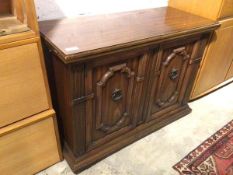 A modern side cabinet, with fold out top, above a pair of panel doors with a single drawer and shelf