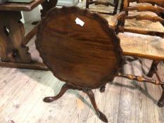 A reproduction Georgian style tilt top occasional table, with circular scalloped piecrust top, on