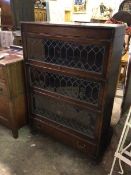 A 1920s oak compartmental bookcase, with three tiers, each with leaded glass fronts (one a/f)