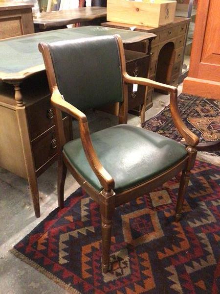 A mid 20thc open desk chair, with green leatherette back and seat, with shaped arms, on turned front